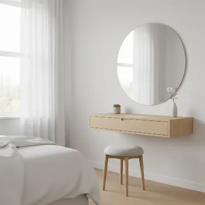A sleek, minimalist floating vanity table in a small bedroom with a built-in circular mirror and subtle storage, against a light-colored wall, natural daylight from a window, contemporary style